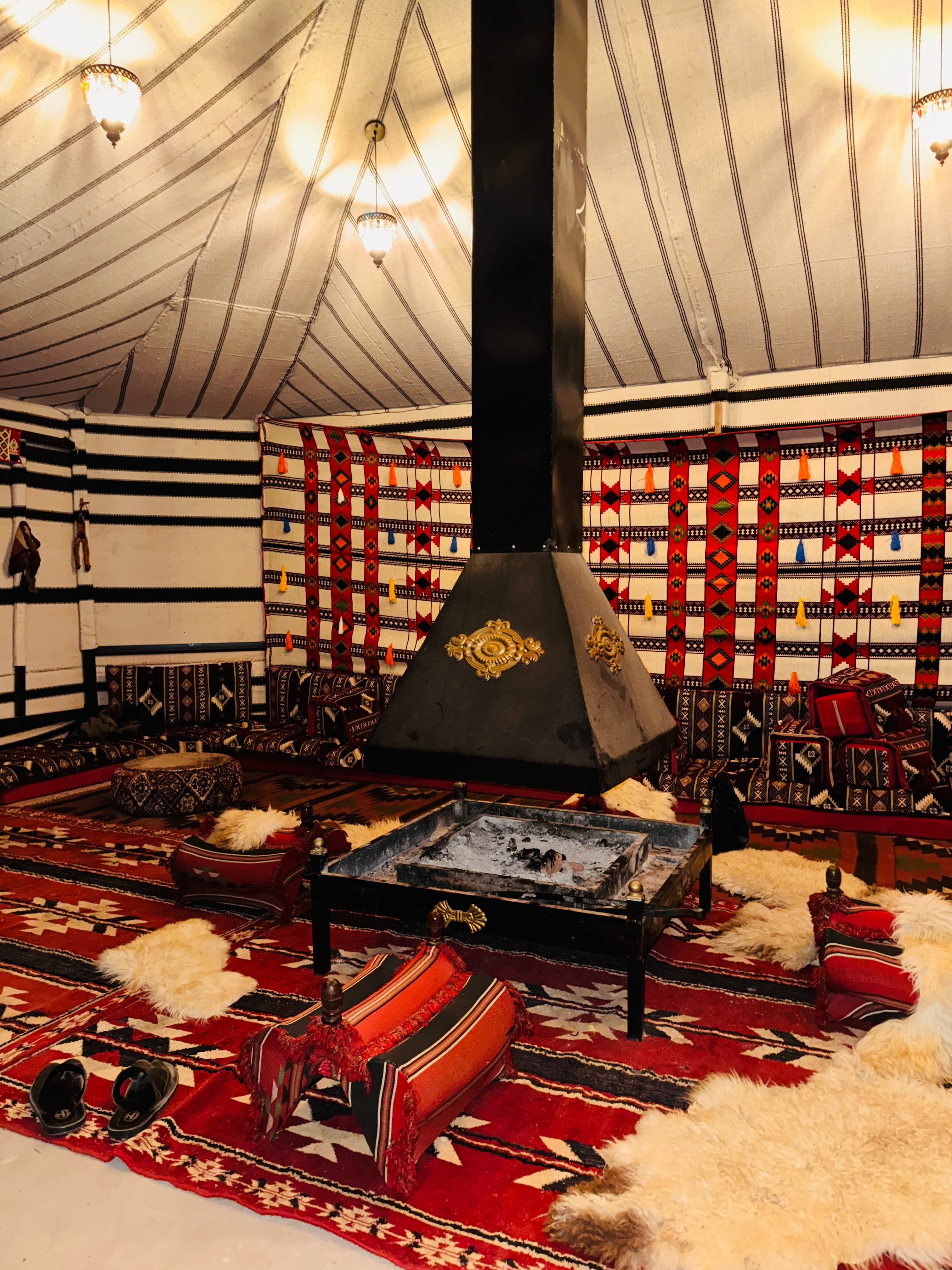 Traditional woven rugs, cushions and fireplace inside the communal Bedouin tent