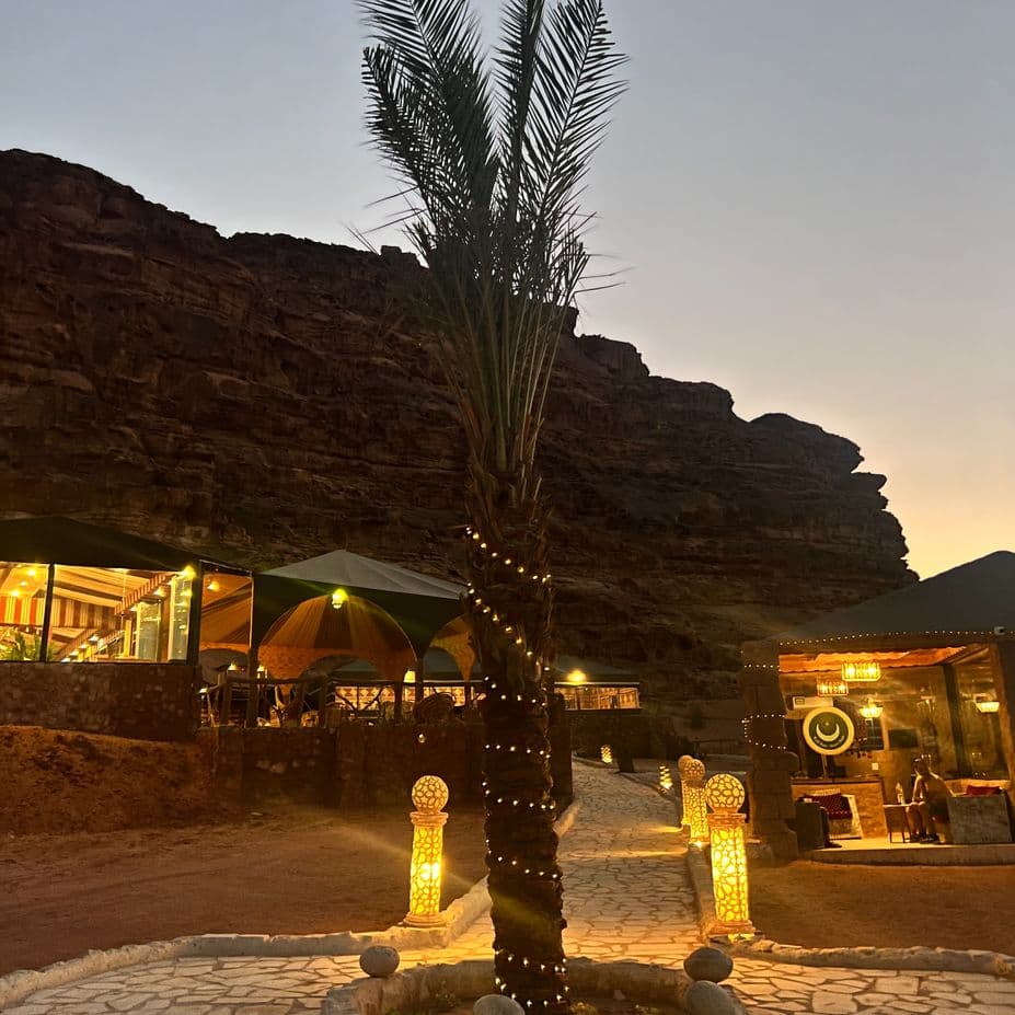 Desert Magic Camp & Resort lit up beneath the cliffs at dusk